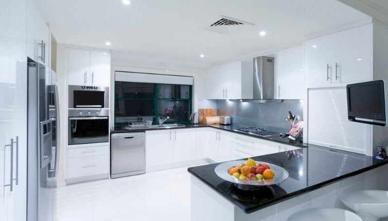 a modern white kitchen with black and chrome appliances and countertops