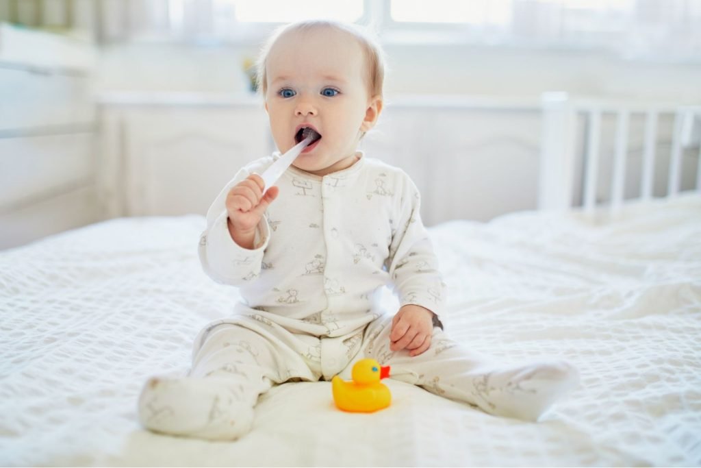 baby in pajamas holding toothbrush